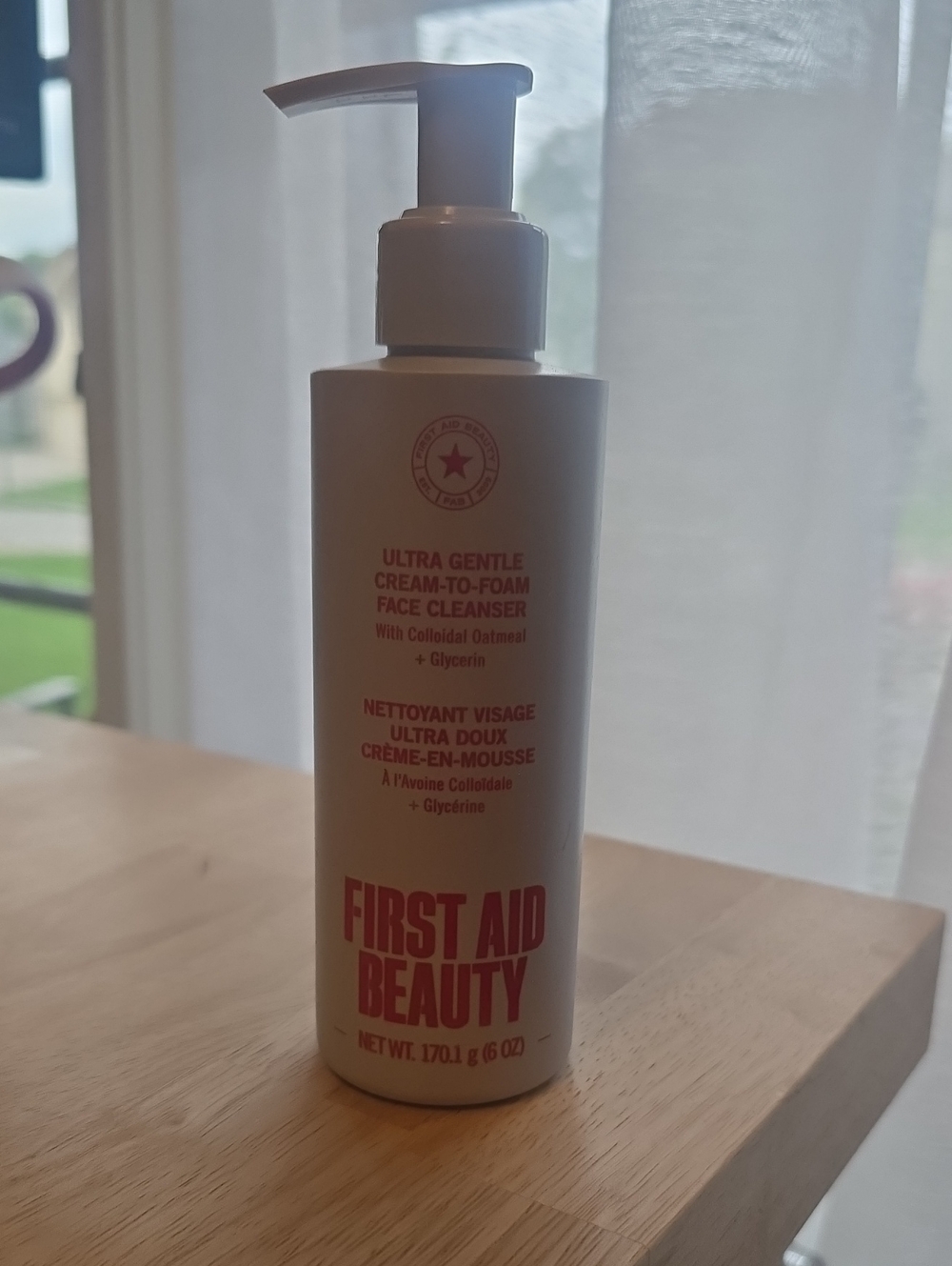 First Aid Beauty Moisturizer Bottle with White and Red Accents